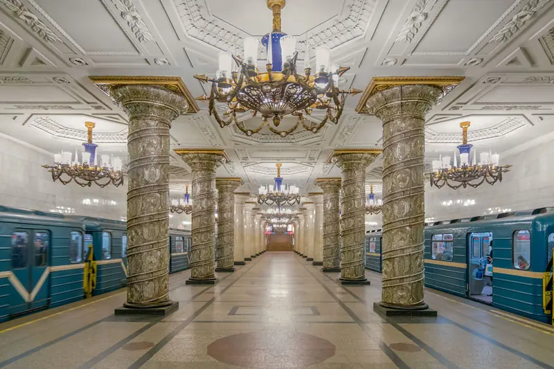Sân ga Avtovo ở St. Petersburg với hàng cột ốp kính chạm hoa văn, đèn chùm pha lê và toa tàu xanh hai bên
